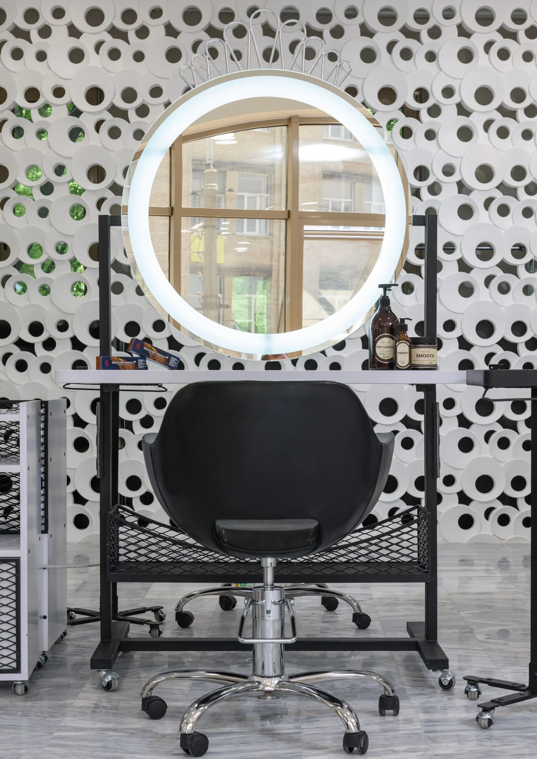 Salon station with a ring light mirror and a black chair